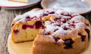 Puszyste ciasto z porzeczkami, posypane cukrem pudrem, wygląda apetycznie. Jeden kawałek już zniknął!