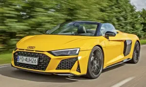 Żółte audi coupe spyder pędzi po drodze, otoczone zielenią drzew.