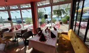 Gemütliche Tische mit rotem Stoff und Blick aufs Wasser – hier könnte das beste Restaurant in Waren sein.