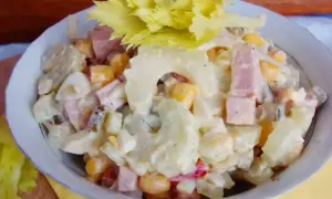 Sałatka z selera naciowego, jajka, kukurydzy i szynki w sosie majonezowym, udekorowana liśćmi selera.