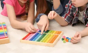 Kinder lernen spielerisch Mathematik im Kindergarten mit bunten Holzbausteinen und einer Multiplikationstafel.