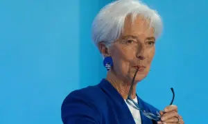Christine Lagarde mit Brille im Mund, nachdenklich vor dem Hintergrund des EZB-Zinsentscheids.