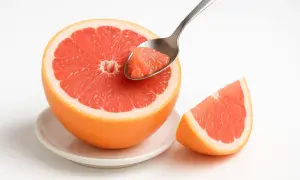 Un pompelmo tagliato a metà, pronto per essere gustato con un cucchiaino. Perfetto per mangiare pompelmo la sera, un fresco spuntino.