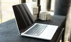 Nowy laptop czeka na pierwsze uruchomienie. Na blacie obok stoją ozdobne świeczniki.