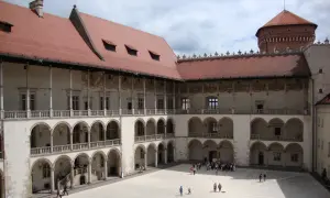 Dziedziniec zamku królewskiego na Wawelu, z arkadowymi krużgankami i wieżą. Ciekawostki o historii tego miejsca czekają na odkrycie.