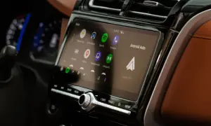 Ekran multimedialny z Android Auto, pokazujący ikony aplikacji: Spotify, Telefon, Mapy. W tle widać fragment deski rozdzielczej.
