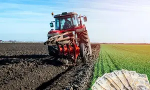 Czerwony traktor orze pole, a obok leżą polskie banknoty. Rolnicy liczą na to, że wzrosną wynagrodzenia w KRUS.