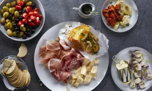 Plateau de charcuterie, fromages, olives, tomates séchées, artichauts, toasts à l'ail et sardines. Une recette antipasti italien facile pour un apéritif gourmand.