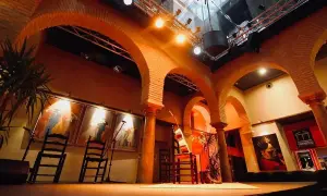 Escenario listo para la gracia flamenca. Sillas, guitarras y cuadros evocan la pasión del arte.