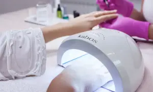 Dłoń w lampie UV do paznokci. Zastanawiasz się, ile trzymać bazę w lampie? Czas utwardzania zależy od produktu.