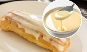 Słodki ekler oblany lukrem, obok miseczka z kremowym custard. Pyszny deser!