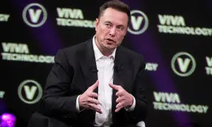 Elon Musk w garniturze, przemawiający na tle logo Viva Technology.