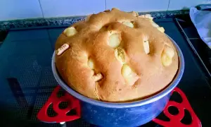 A golden-brown, round bread with chunks of white cheese baked into the top, in a blue baking pan.