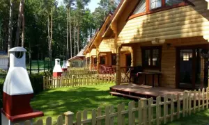 Nawrapark Pobierowo domki letniskowe: drewniane domki z tarasami i grillami, otoczone zielenią i lasem.