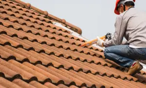 Handwerker repariert die Dachrinne mit einer Kartuschenpistole.