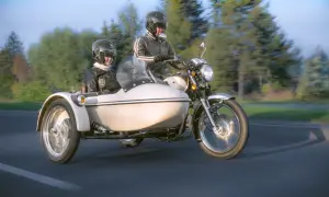 Para podróżuje motocyklem z koszem, ciesząc się jazdą po malowniczej drodze.