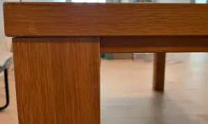 Detaljbild av ett träbord i fanér, redo för renovering.