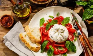 Ser burrata z pomidorami i bazylią, podany z chrupiącym pieczywem. Idealny pomysł na to, ser burrata z czym jeść.