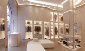 Interni negozio di abbigliamento con abiti eleganti appesi, borse e scarpe in esposizione. L'ambiente è moderno e luminoso, con un design minimalista e finiture in legno chiaro.