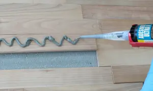 Aplicando adhesivo para parquet con pistola. Preparando para barnizar parquet.