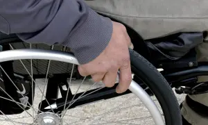 Mano che afferra la ruota di una sedia a rotelle per anziani, un ausilio essenziale fornito dall'ASL per garantire mobilità e autonomia.