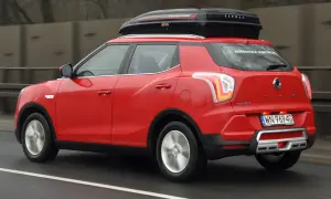 Czerwony SsangYong Tivoli z boxem dachowym, gotowy na podróż. Wiele pozytywnych ssangyong tivoli opinie potwierdza jego wszechstronność.