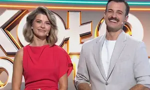 Uśmiechnięci prowadzący Koło Fortuny: ona w czerwonej sukience, on w jasnej marynarce.