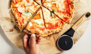 Une main prend une part de pizza maison, fraîchement coupée, prête à être dégustée. Idéal pour congeler pizza maison et en profiter plus tard.