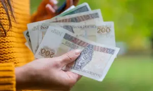 Dłoń trzyma polskie banknoty 200 zł. To może być dodatek wyrównawczy, który pomoże w codziennych wydatkach.
