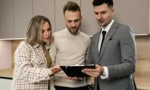 Para młodych ogląda ofertę mieszkania z agentem nieruchomości. Wynajmujący omawia szczegóły umowy.