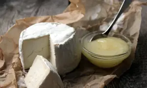 En krämig ost med en bit bortskuren, bredvid en skål med honung. Perfekt för en gravid som längtar efter fetaost.