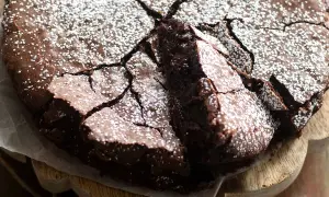 Deliziosi dolci con cioccolato fondente, una torta scura e umida con una crosta screpolata e cosparsa di zucchero a velo.