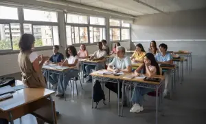 Nauczycielka prowadzi lekcję wychowania do życia w rodzinie. Uczniowie uważnie słuchają, siedząc w ławkach.