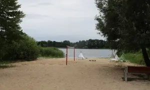 Plaża nad jeziorem Lednica z siatką do siatkówki i namiotami tipi.