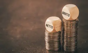Dwie wieże monet, jedna z kostką "NETTO", druga z "BRUTTO". Czy to odzwierciedla średnią krajową netto?