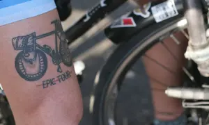 Tatuaż rowerowy z napisem "EPIC TOUR" na ramieniu rowerzysty.