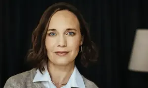Kvinna med blå ögon och brunt hår, klädd i kofta och skjorta. Hon ser ut att ha en tankfull blick, kanske funderar hon på relations-ocd.