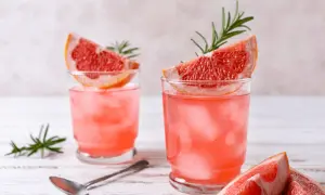 Orzeźwiająca lemoniada grejpfrutowa z plasterkami owoców i gałązkami rozmarynu, podana z lodem.