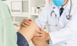 Lekarz bada kolano pacjenta, sprawdzając, czy woda w kolanie sama zejdzie.