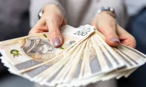 Dłonie trzymające plik banknotów 200 zł. Czy to odpowiedź na pytanie, ile zarabia menedżer hotelu?