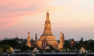 Zachód słońca nad rzeką w Bangkoku, stolicy Tajlandii pełna nazwa. Wspaniała świątynia Wat Arun rozświetlona złotym blaskiem.