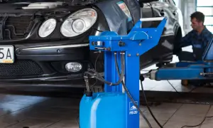 Mechanik przeprowadza wymianę płynu hamulcowego w czarnym samochodzie, używając specjalistycznego sprzętu.