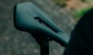 Ciemne siodełko rowerowe z wycięciem, zamocowane na sztycy. Gotowe na jazdę.