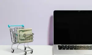 Mini wózek sklepowy z banknotami i laptopem. Klik i pachniesz opinie o zakupach online.