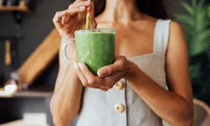 Donna sorseggia un frullato verde, un'ottima opzione su cosa bere per dimagrire.