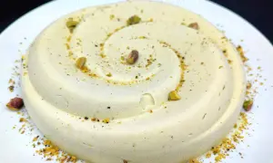 Delizioso semifreddo al pistacchio, decorato con granella e pistacchi interi, servito su un piatto bianco.
