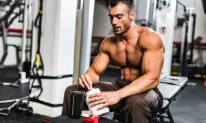 Muskulöser Mann im Fitnessstudio bereitet Proteinshake zu. Was hilft beim Muskelaufbau? Richtige Ernährung und Supplemente sind wichtig.