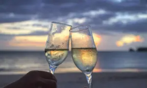 Dwie kieliszki szampana na tle zachodzącego słońca nad morzem. Idealna randka w domu, nawet jeśli dom jest na plaży.