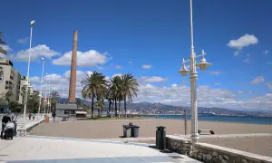 Paseo marítimo con palmeras y chimenea industrial. La playa Misericordia, ideal para llegar y disfrutar del mar.
