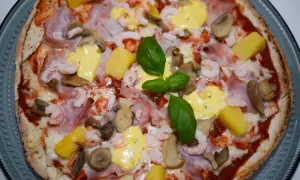 En läcker pizza med räkor och skinka, toppad med ananas, champinjoner och en krämig sås. En riktig smakupplevelse!